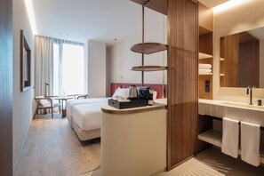 A hotel room with a bed, bedside table, lamp, and a bathroom with a sink and mirror. - Eurostars Valladolid (Valladolid)