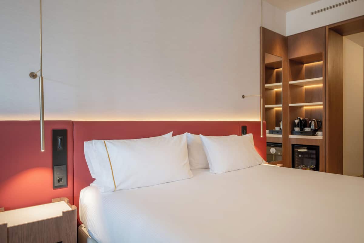 A hotel room with a bed, bedside table, and built-in wardrobe.