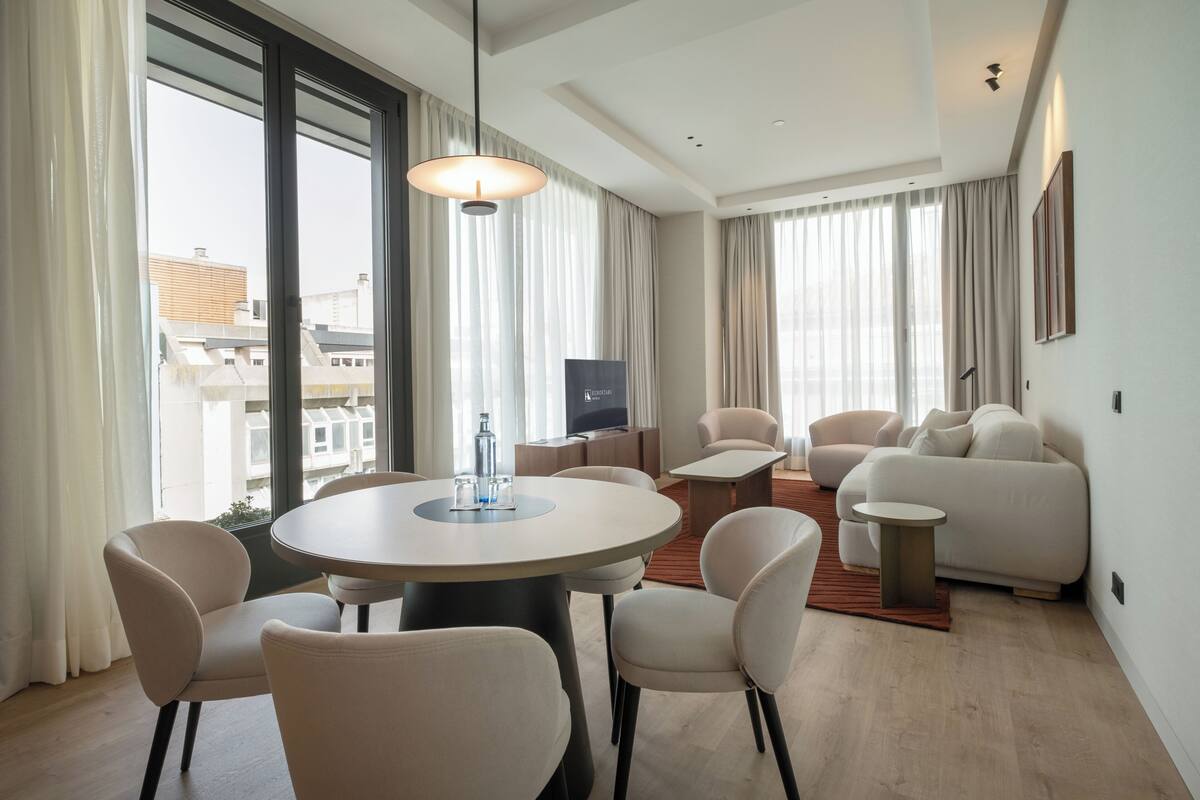 A modern living room with a round dining table, chairs, a sofa, and a TV.