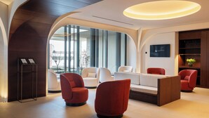 A modern lobby with a reception desk, seating area, and a television screen. - Eurostars Valladolid (Valladolid)