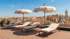 A rooftop terrace with lounge chairs and umbrellas, overlooking a cityscape with historic buildings. - Eurostars Valladolid (Valladolid)