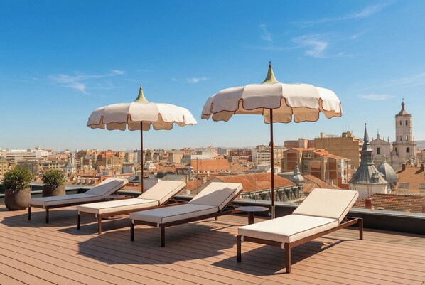 A rooftop terrace with lounge chairs and umbrellas, overlooking a cityscape with historic buildings. - Eurostars Valladolid (Valladolid)