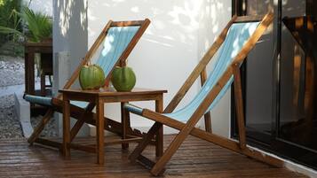 Dos sillones de madera con cojines azules y una mesita de madera con dos cocos verdes.