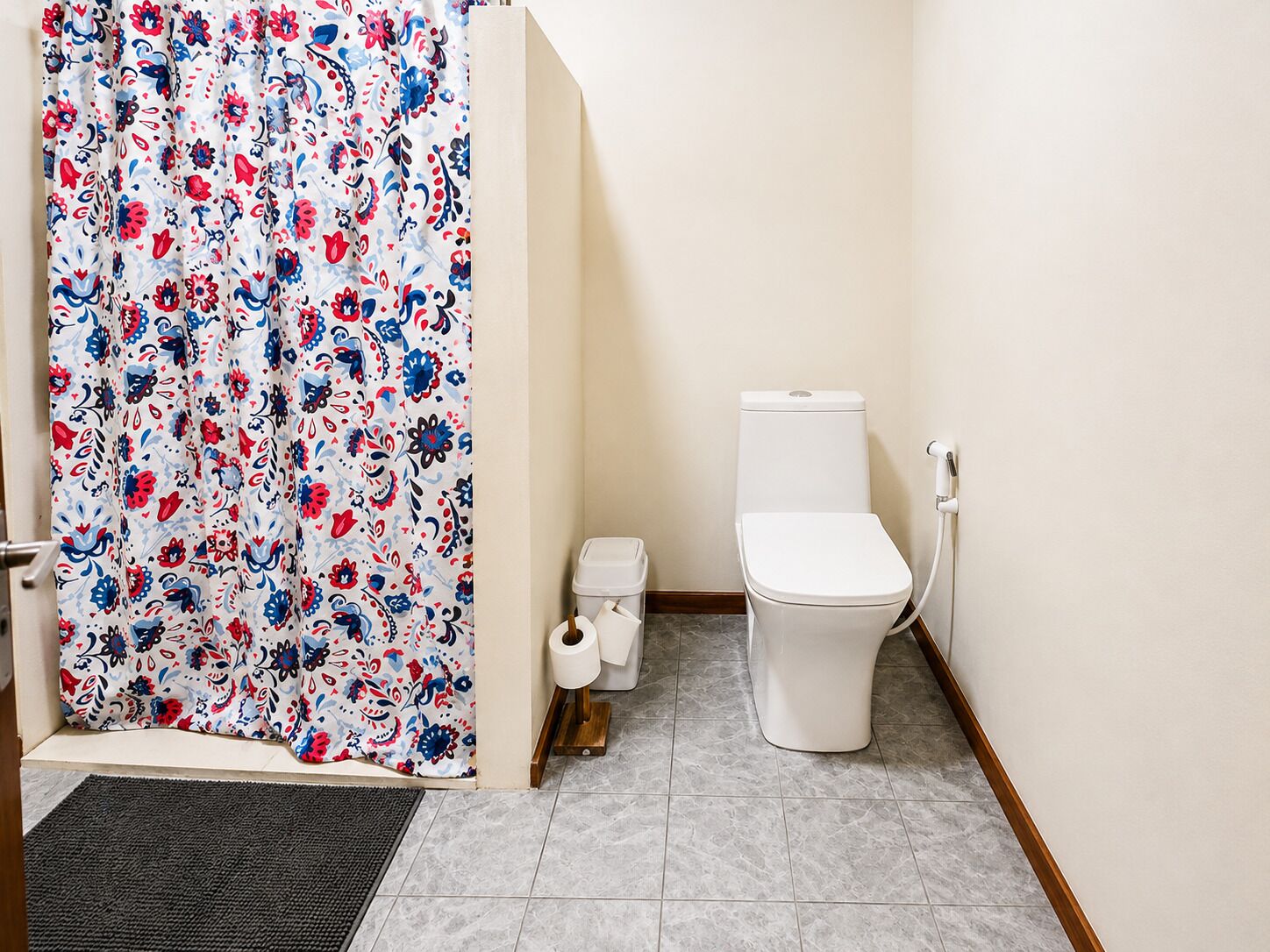 A bathroom with a toilet, a bidet, and a shower curtain with a floral pattern.