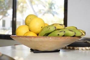 Un frutero con fruta sobre una mesa, con una ventana al fondo.