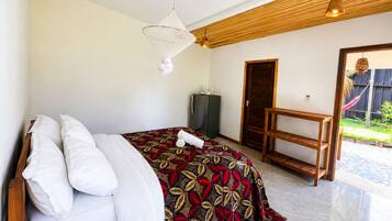 Un dormitorio con cama, un banco de madera, una puerta y una lámpara colgante.