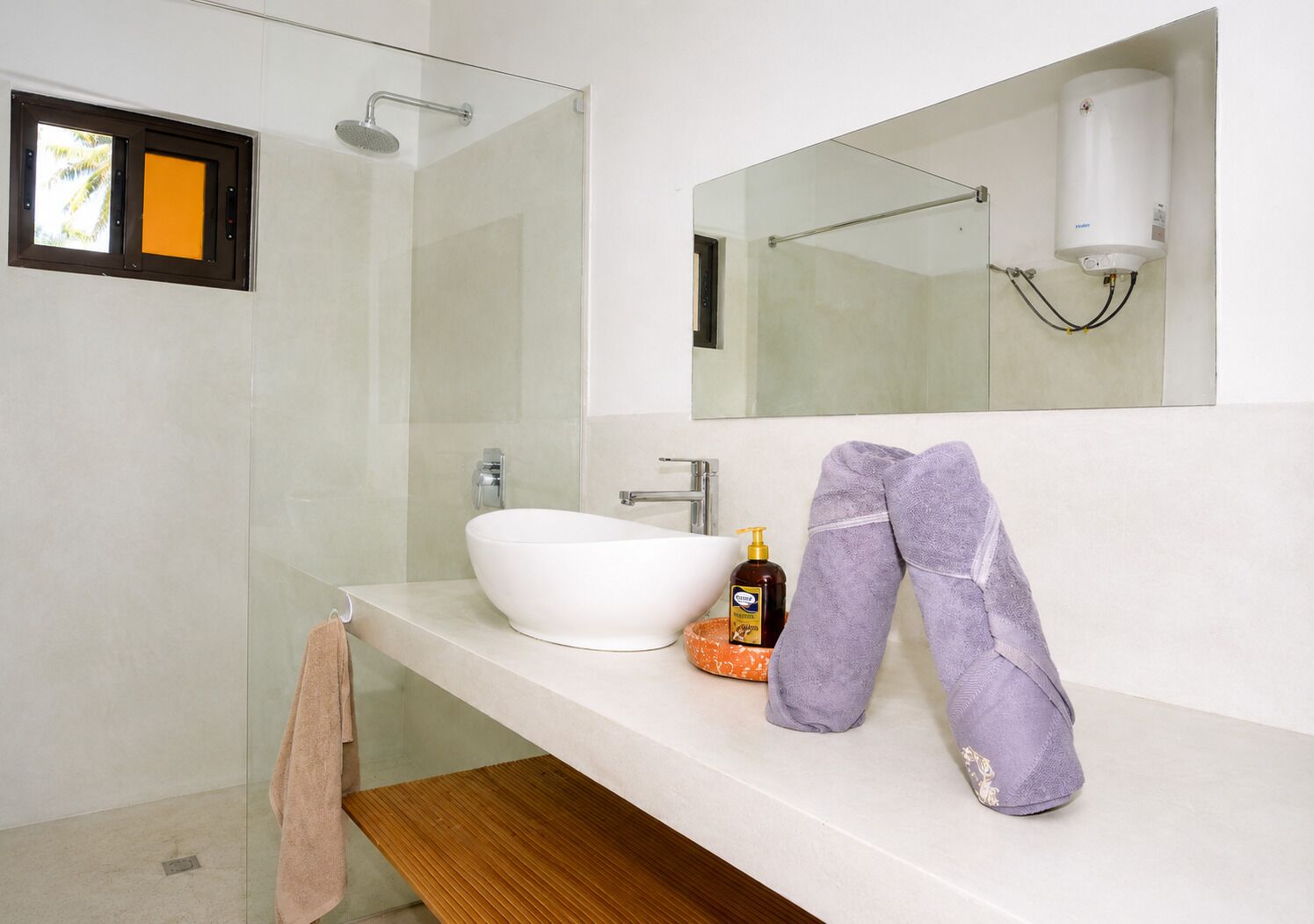 A modern bathroom with a glass shower enclosure, a white sink, and a mirror above the sink.