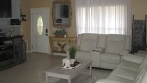 A living room with a ceiling fan, a sofa, a coffee table, and a television.