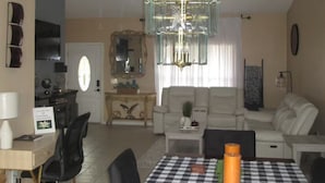 A spacious living area with a dining table set for four, a chandelier, and a sofa.
