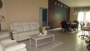 A living room with a white sofa, a coffee table, and a dining area with a table and chairs.