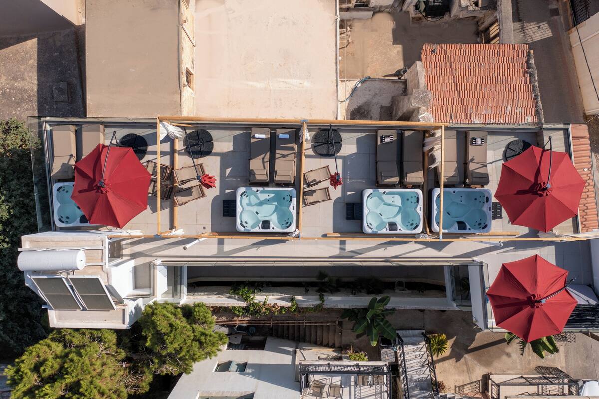 A rooftop terrace with multiple hot tubs, each with a red umbrella.