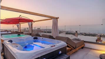 A rooftop terrace with hot tubs, outdoor seating, and a view of the cityscape.