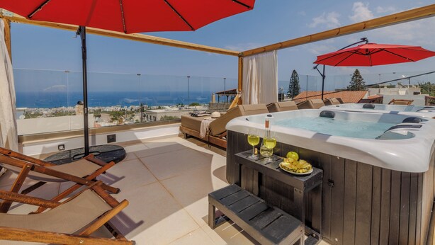 A rooftop terrace with a hot tub, lounge chairs, and a red umbrella. - Angel Apartments 2 (Koutouloufari)