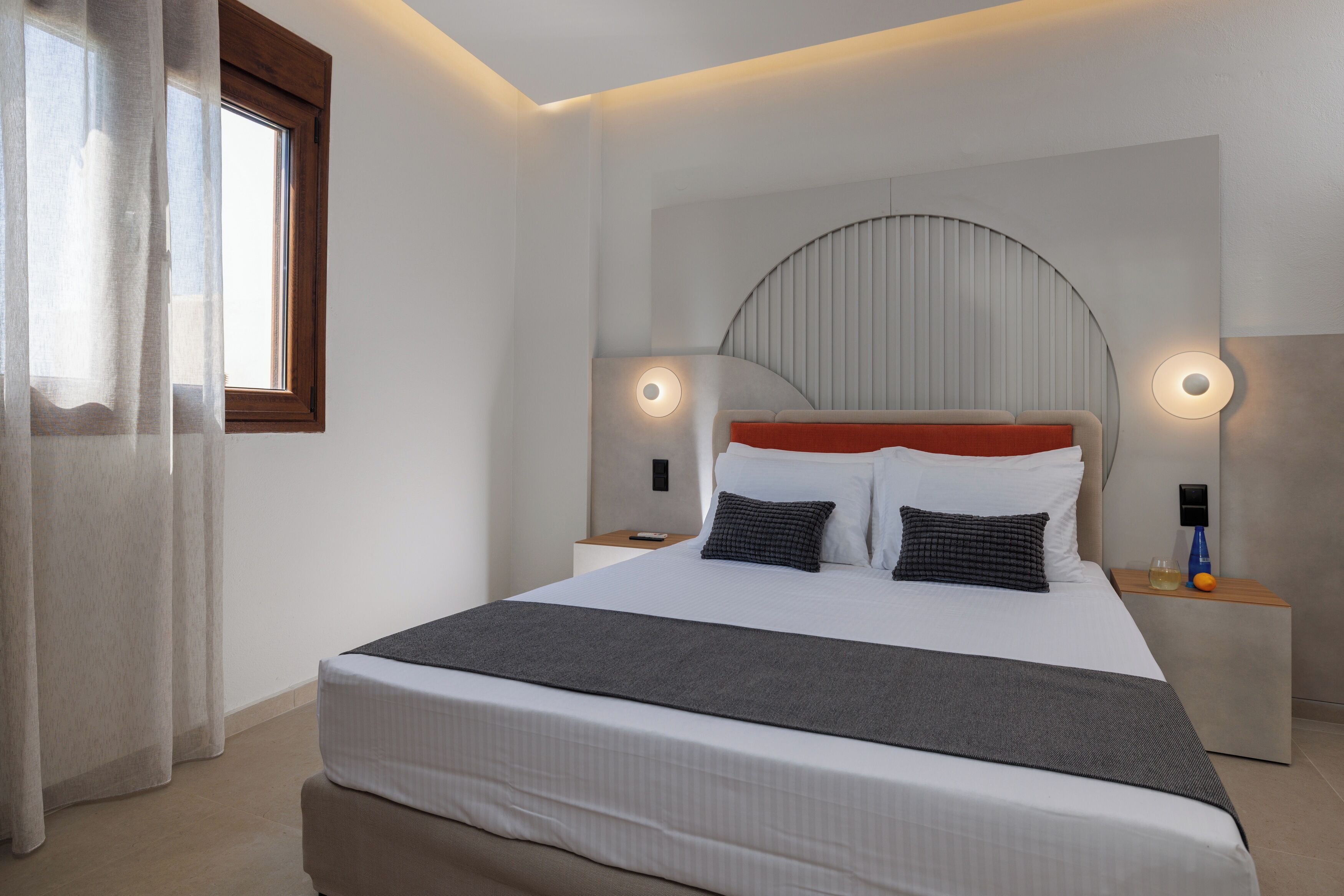 Une chambre moderne avec un grand lit, des tables de chevet et une tête de lit incurvée originale.
