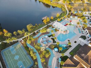 Vue aérienne d’un complexe hôtelier doté d’une piscine, d’un terrain de basketball et d’un toboggan aquatique.