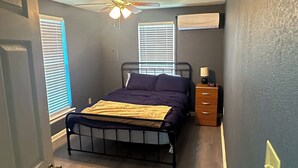 A bedroom with a bed, a nightstand, a ceiling fan, and a window with blinds. - Home Away From Home! (Amarillo)