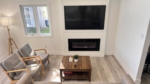 A living room with a large flat-screen TV, a fireplace, a sofa, and a coffee table. - 6BR Waterfront Escape | Perfect for Multi-Family Groups (Harcourt)