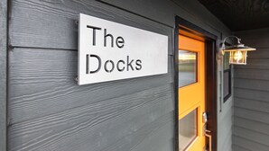 Et skilt med teksten "The Docks" monteret på en grå trævæg.