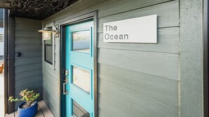 Una puerta azul verdoso con un letrero que dice "The Ocean" en la fachada de un edificio de madera.