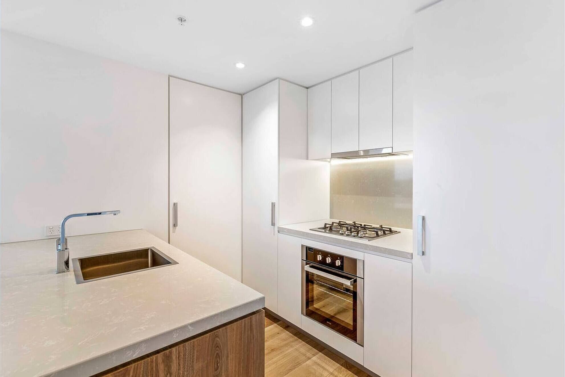 Een moderne keuken met witte kasten, een ingebouwde oven en een roestvrijstalen afzuigkap.