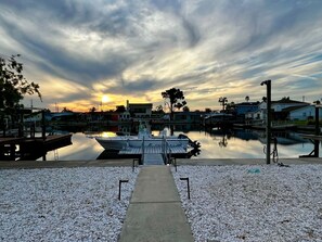 A marina with boats docked, a calm water body, and a sunset in the background.