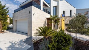 A modern two-story house with a garage, large windows, and a well-maintained garden.