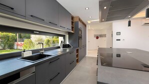 A modern kitchen with grey cabinets, a stainless steel sink, and a built-in oven.
