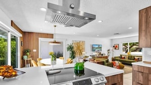A modern kitchen with a central island, built-in oven, and a stainless steel range hood.