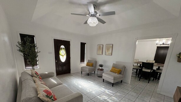 Ein Wohnzimmer mit grauem Sofa, einem kleinen Beistelltisch und einem Deckenventilator.