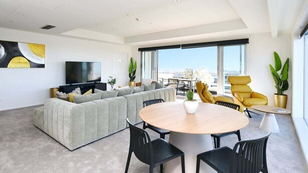 Un salon moderne avec un grand canapé, une table à manger ronde et des chaises jaunes.