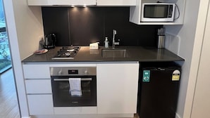 Una cucina compatta con mobili bianchi, un forno a microonde integrato, una lavastoviglie e una macchina da caffè.