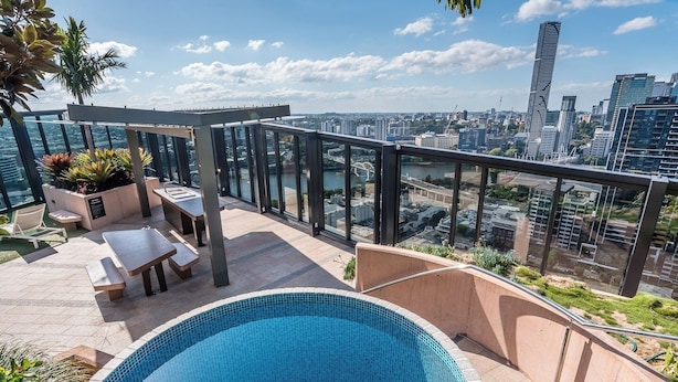 Area piscina sul tetto con vista sulla città, tra cui edifici moderni e un fiume.