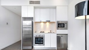 A modern kitchen with stainless steel appliances, white cabinetry, and a black floor lamp.