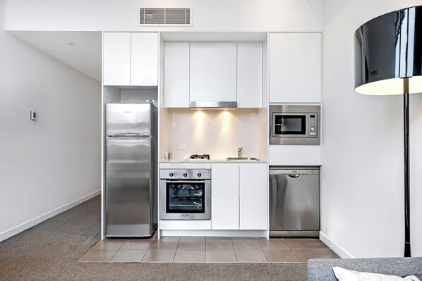 A modern kitchen with stainless steel appliances, white cabinetry, and a black floor lamp. - CozyandModern Rental Studo Apt in Heart of Chatswood (Chatswood)