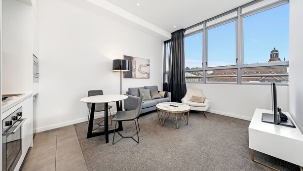 A modern living room with a dining area, a sofa, a coffee table, and a TV.