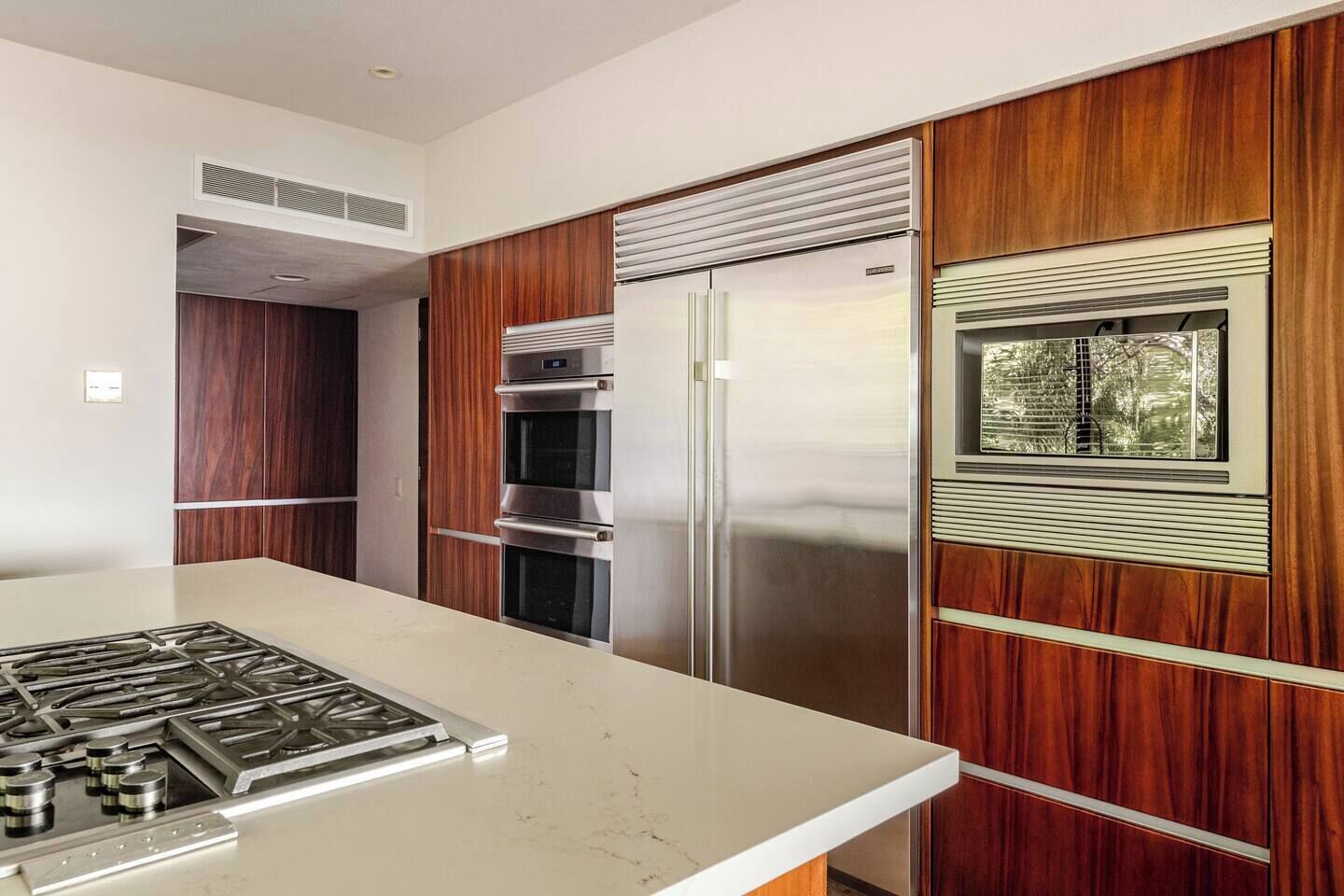Eine moderne Küche mit einem Edelstahl-Kühlschrank, einem eingebauten Backofen und einem Gasherd.