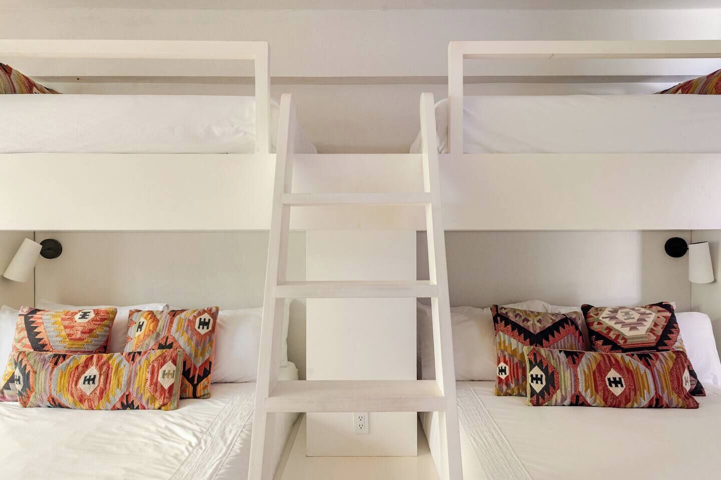 Habitación con literas, dos mesitas de noche y almohadas estampadas.
