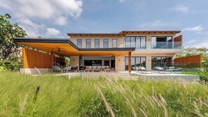 A modern two-story house with a covered patio, a swimming pool, and a lush garden. - Iyari Estates Punta Mita Villa with Ocean Views and Pool (Corral del Risco)