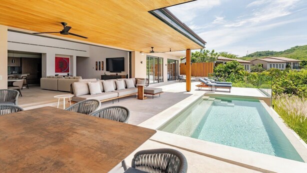A modern outdoor living area with a pool, seating, and a view of the surrounding landscape. - Iyari Estates Punta Mita Villa with Ocean Views and Pool (Corral del Risco)