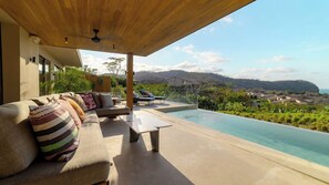 A modern outdoor seating area with a pool, overlooking a scenic landscape.