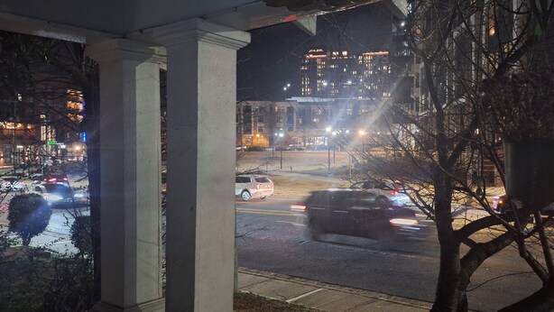 A nighttime view from a covered outdoor area with a street in the background.