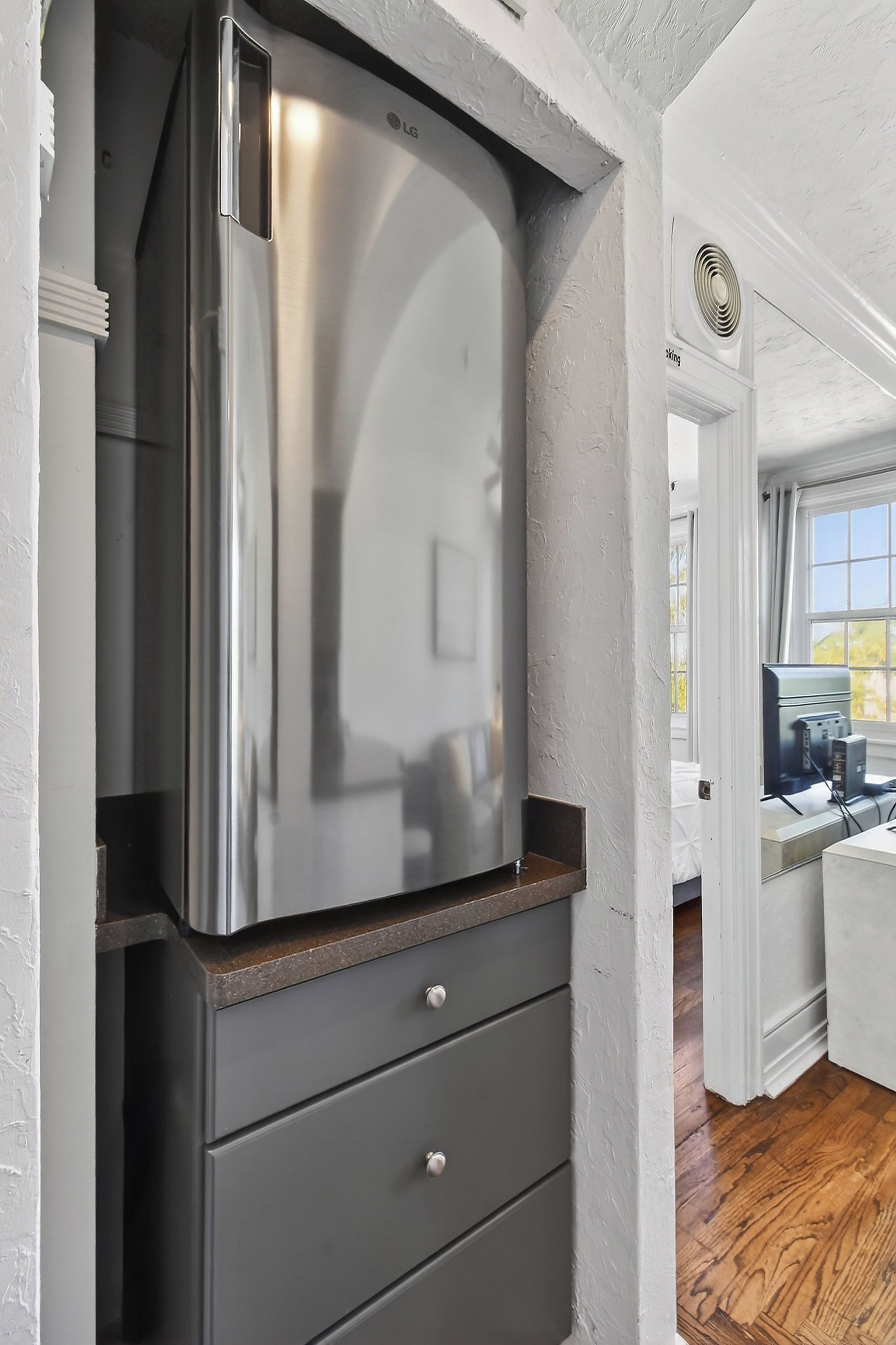 A modern kitchen with a stainless steel refrigerator, a wooden countertop, and a built-in drawer unit.