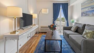 A modern living room with a flat-screen TV, a sofa, a coffee table, and a TV stand with lamps.