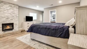 A bedroom with a fireplace, a bed, a TV, and a wardrobe.