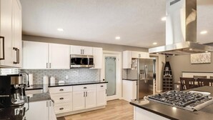 A modern kitchen with white cabinets, a stainless steel range, and a microwave.