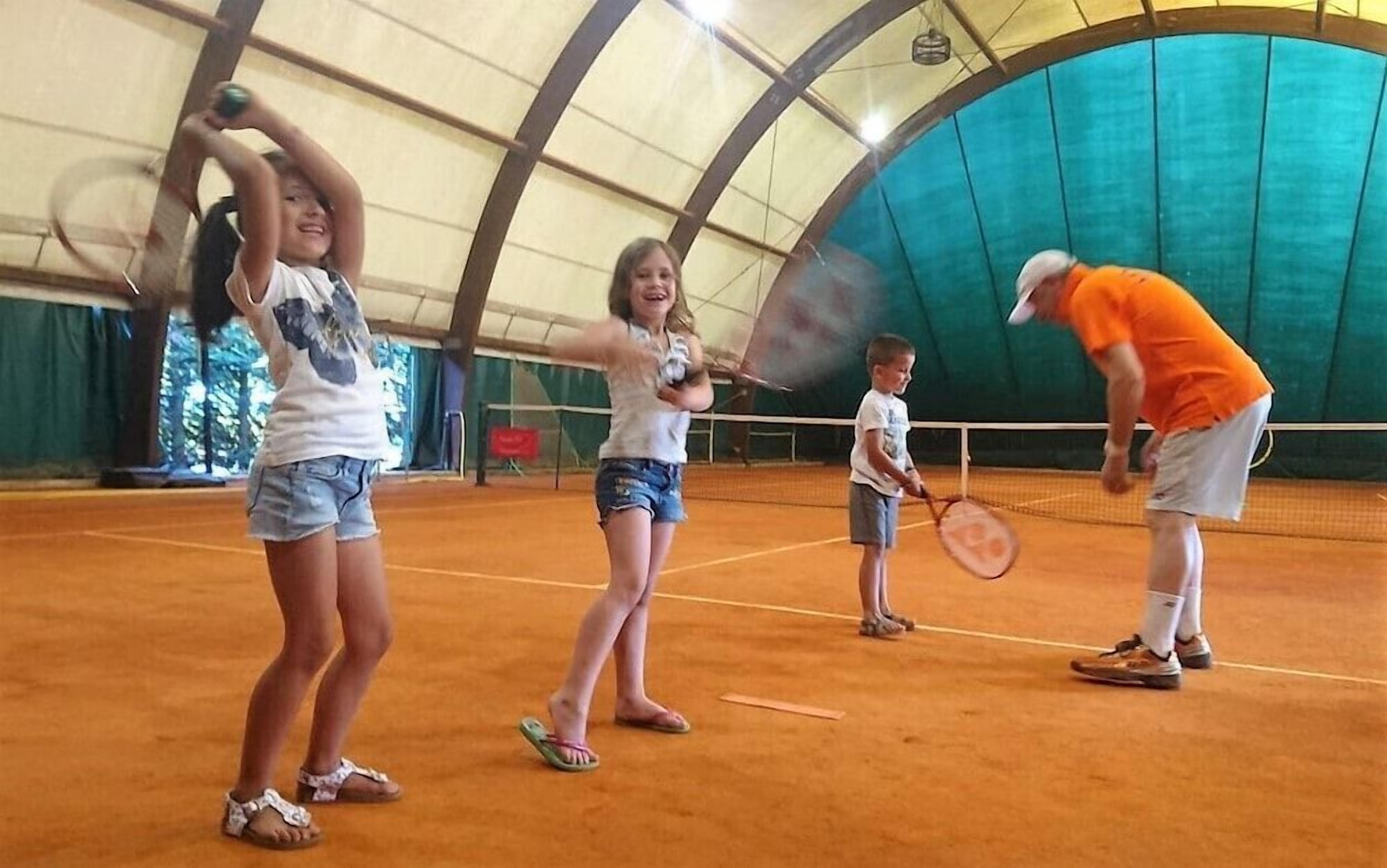 Una cancha de tenis con jugadores y un entrenador.