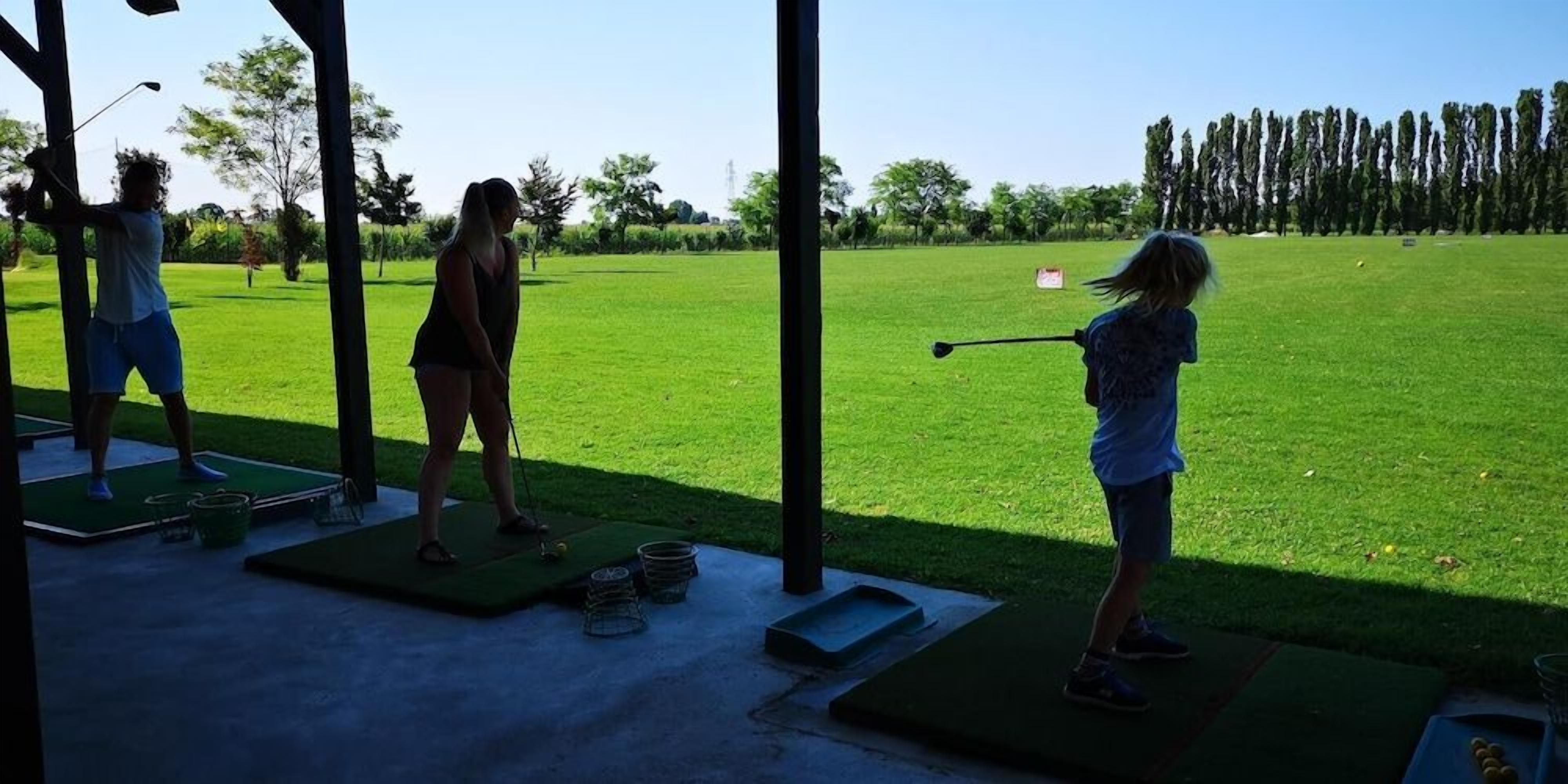 Zona de práctica de golf al aire libre con varios tee boxes y un putting green.