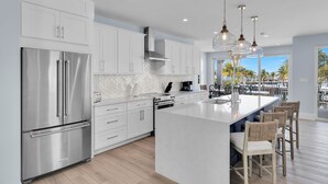 A modern kitchen with stainless steel appliances, white cabinetry, and a large island with bar seating. - Luxury Waterfront Home - Marathon, FL Keys - 5BR, Private Pool, Dock - Sleeps 10 (Marathon)