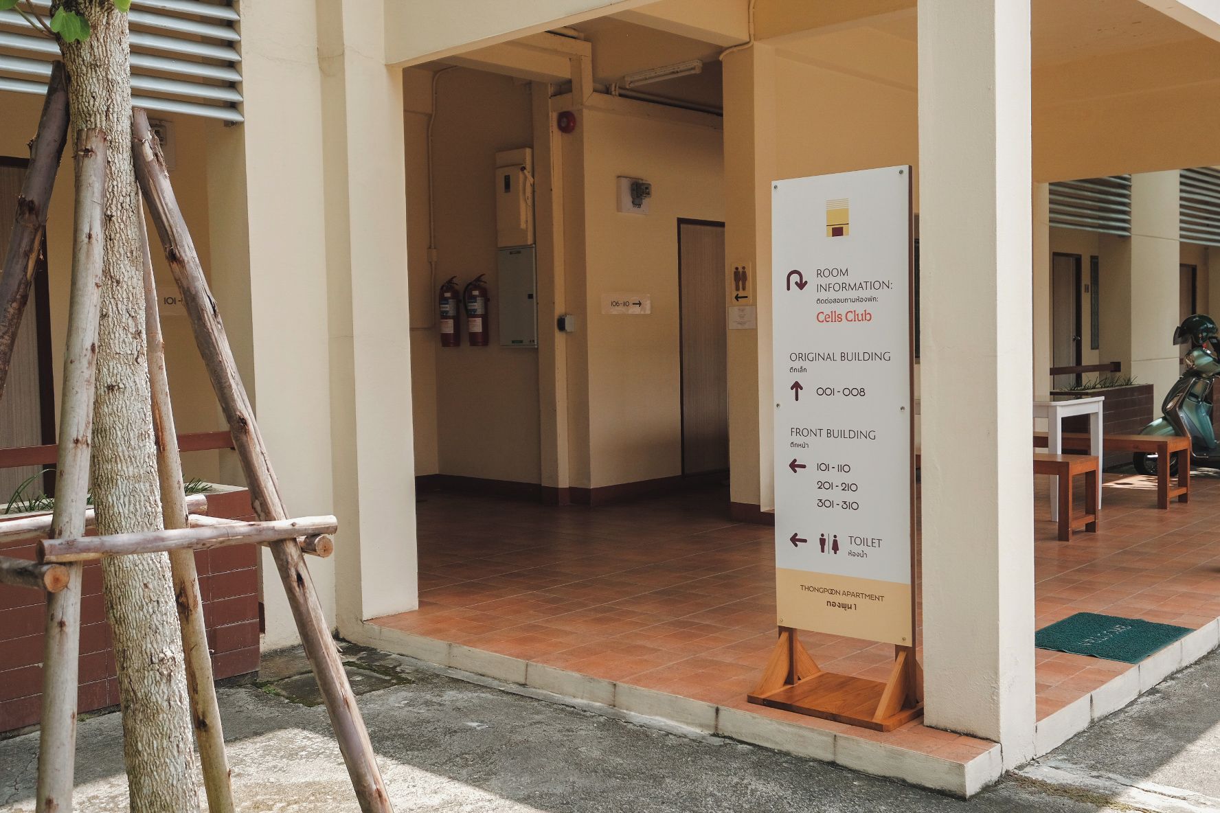 A hotel entrance with a sign indicating room information, including the Cells Club and Thonpland Apartment.