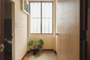 A room with a window, a radiator, a potted plant, and a door. - Thong Poon Apartment Chiang Mai (Chiang Mai)